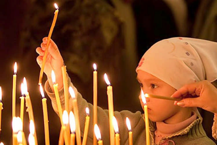 Ребенок ставит свечу